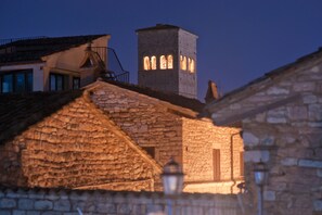 A stone building with a tower featuring arched windows, a balcony, and a stone facade. - Hotel Il Duomo (Assisi)
