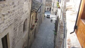 Una estrecha calle empedrada flanqueada por edificios históricos de piedra, con ventanas y puertas visibles.