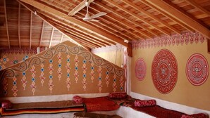 Une pièce avec un plafond en pente, un banc en bois avec des coussins rouges et des motifs décoratifs sur les murs.