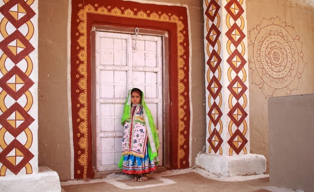 A person standing in front of a door with intricate patterns and designs on the walls.