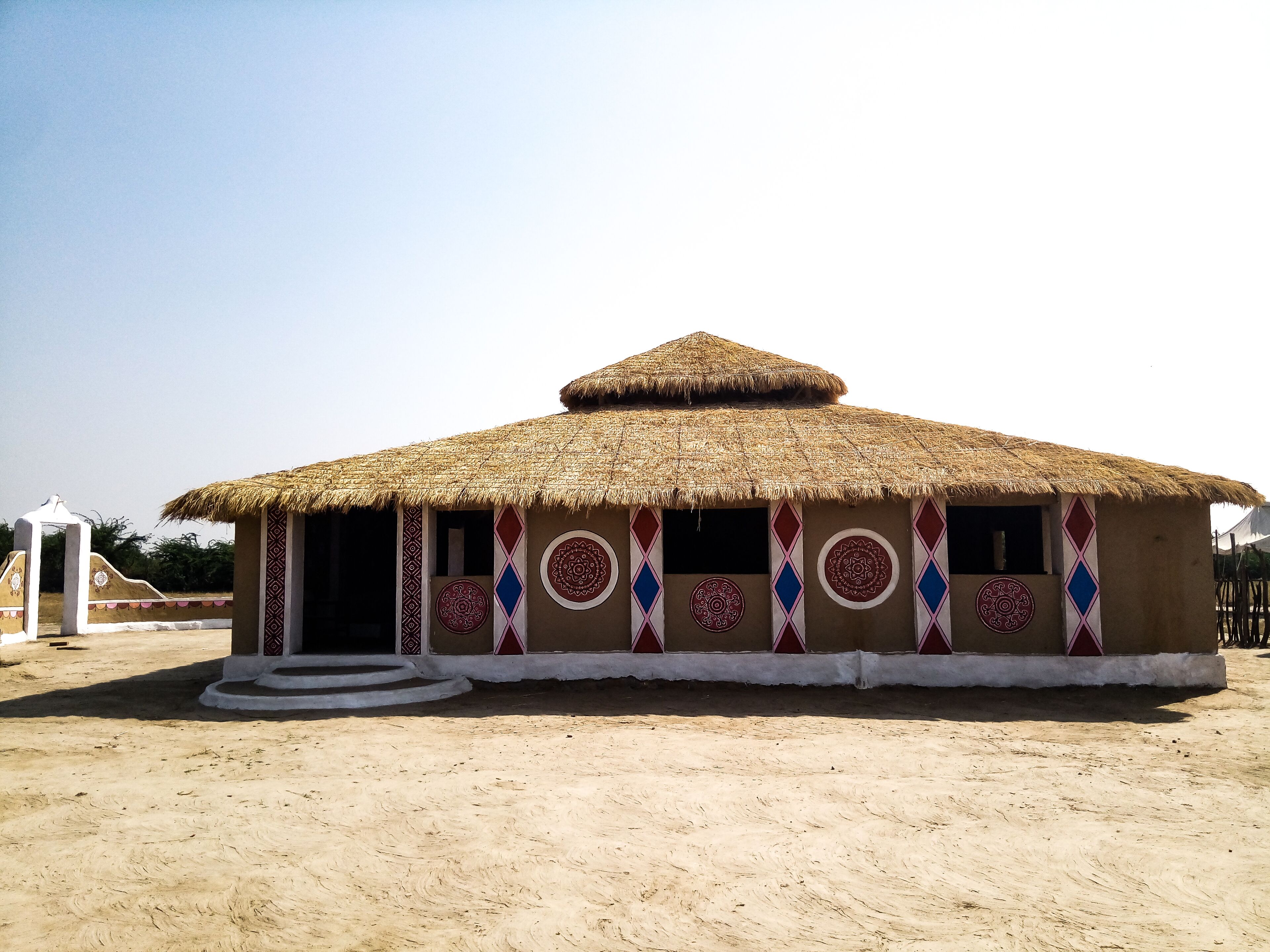 Uma cabana tradicional com telhado de palha e padrões decorativos nas paredes.