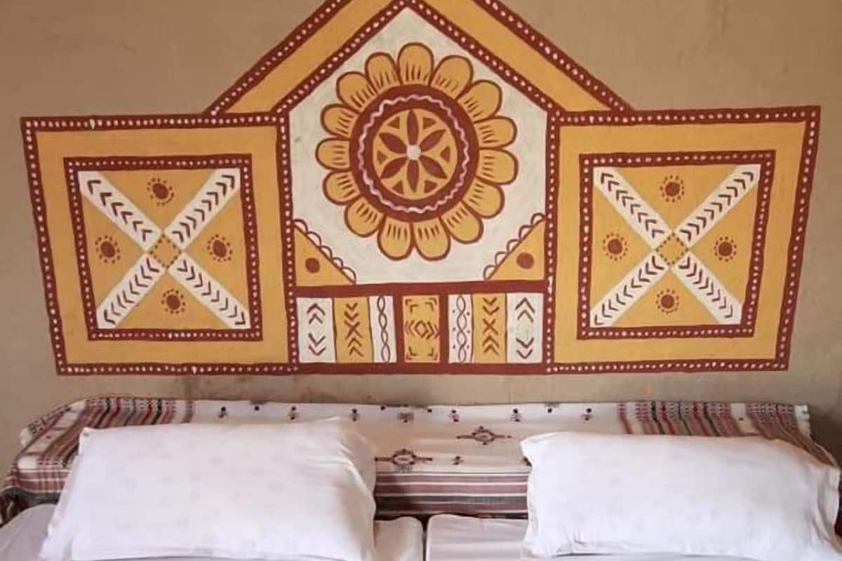 A double bed with white linens and a headboard featuring a geometric pattern.