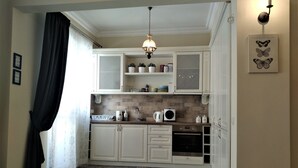 A kitchen with white cabinets, a patterned tile floor, and a hanging light fixture. - Baratero City Corner Apartment (Sofia)