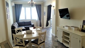 A dining area with a round table, white chairs, and a chandelier. - Baratero City Corner Apartment (Sofia)