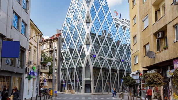 A modern building with a geometric glass facade and a prominent entrance. - Baratero City Corner Apartment (Sofia)