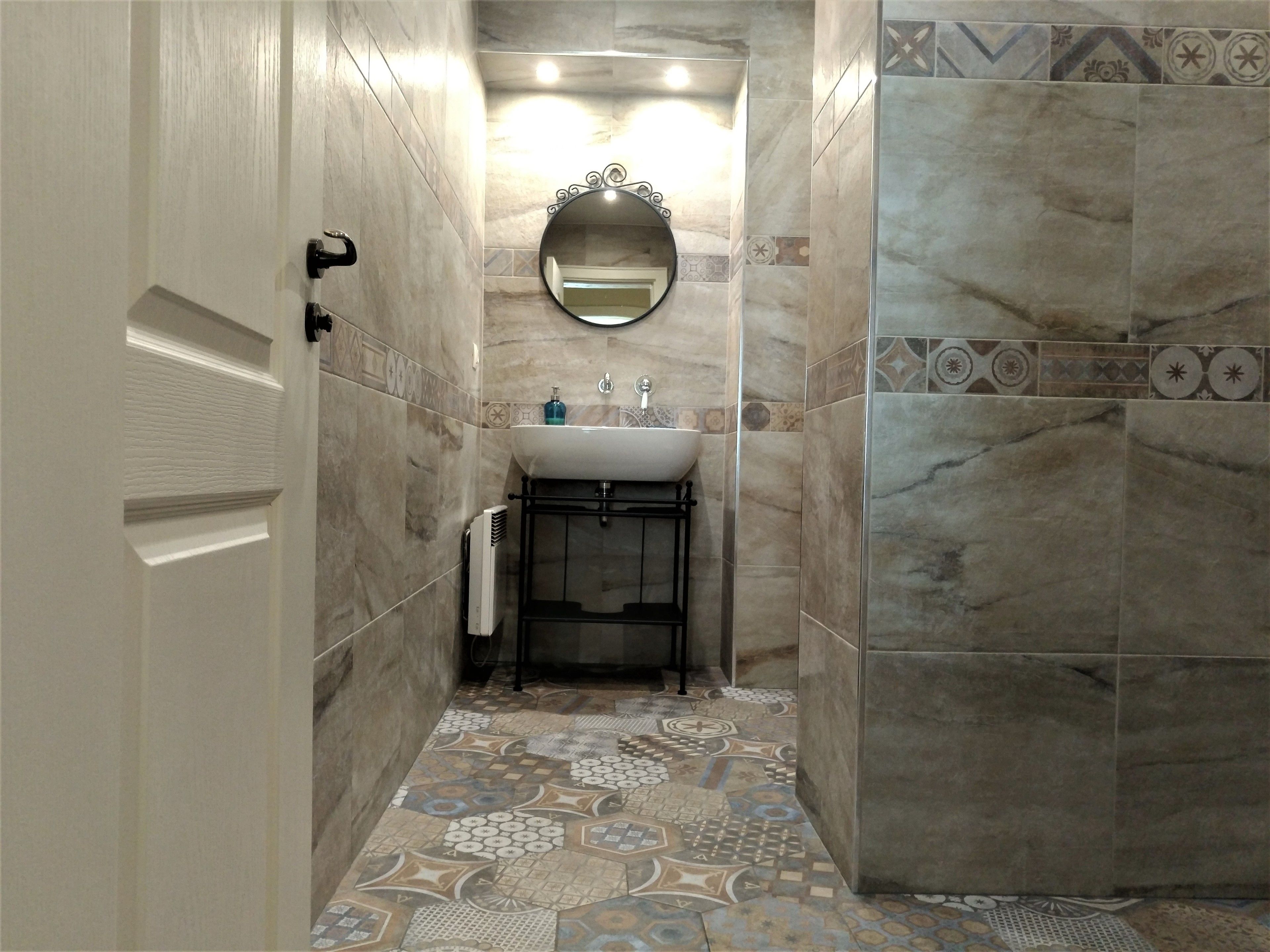 Une petite salle de bain avec un lavabo blanc, un miroir et des carreaux décorés.