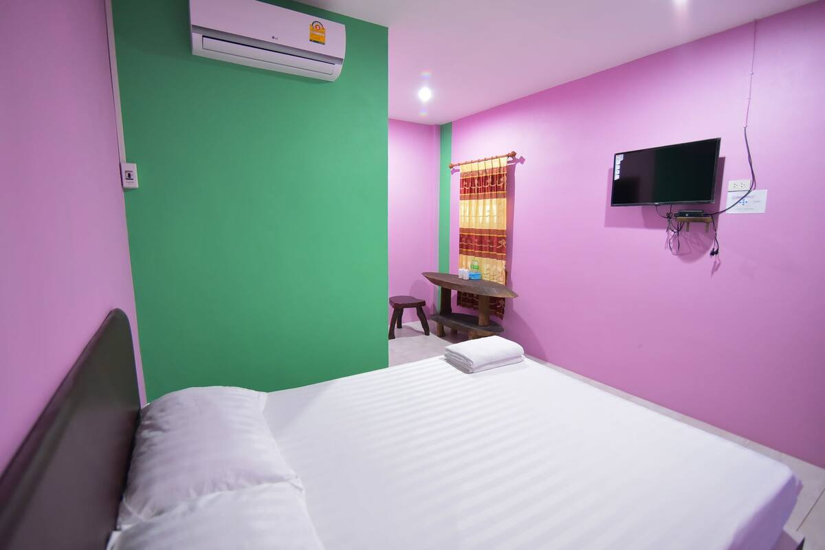 A room with a bed, a desk, a chair, a television, and an air conditioner.
