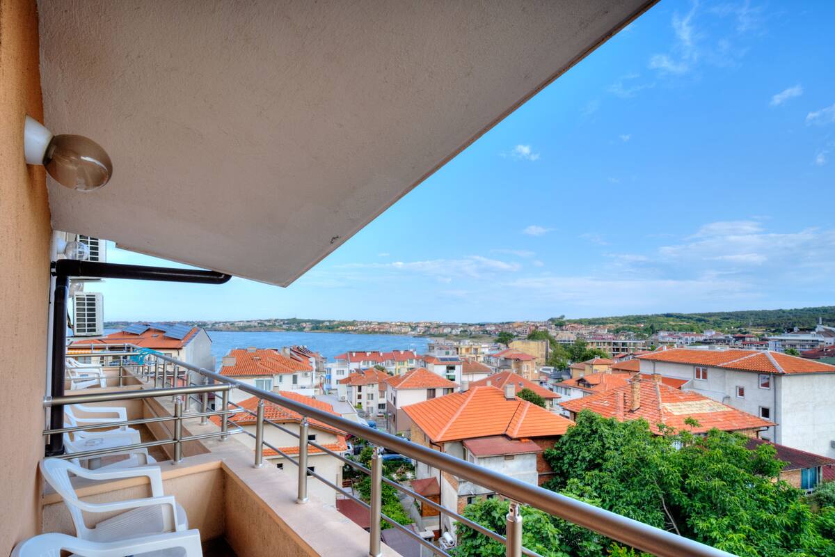 Ein Balkon mit Blick auf eine Küstenstadt, Geländer und einem klaren Himmel.