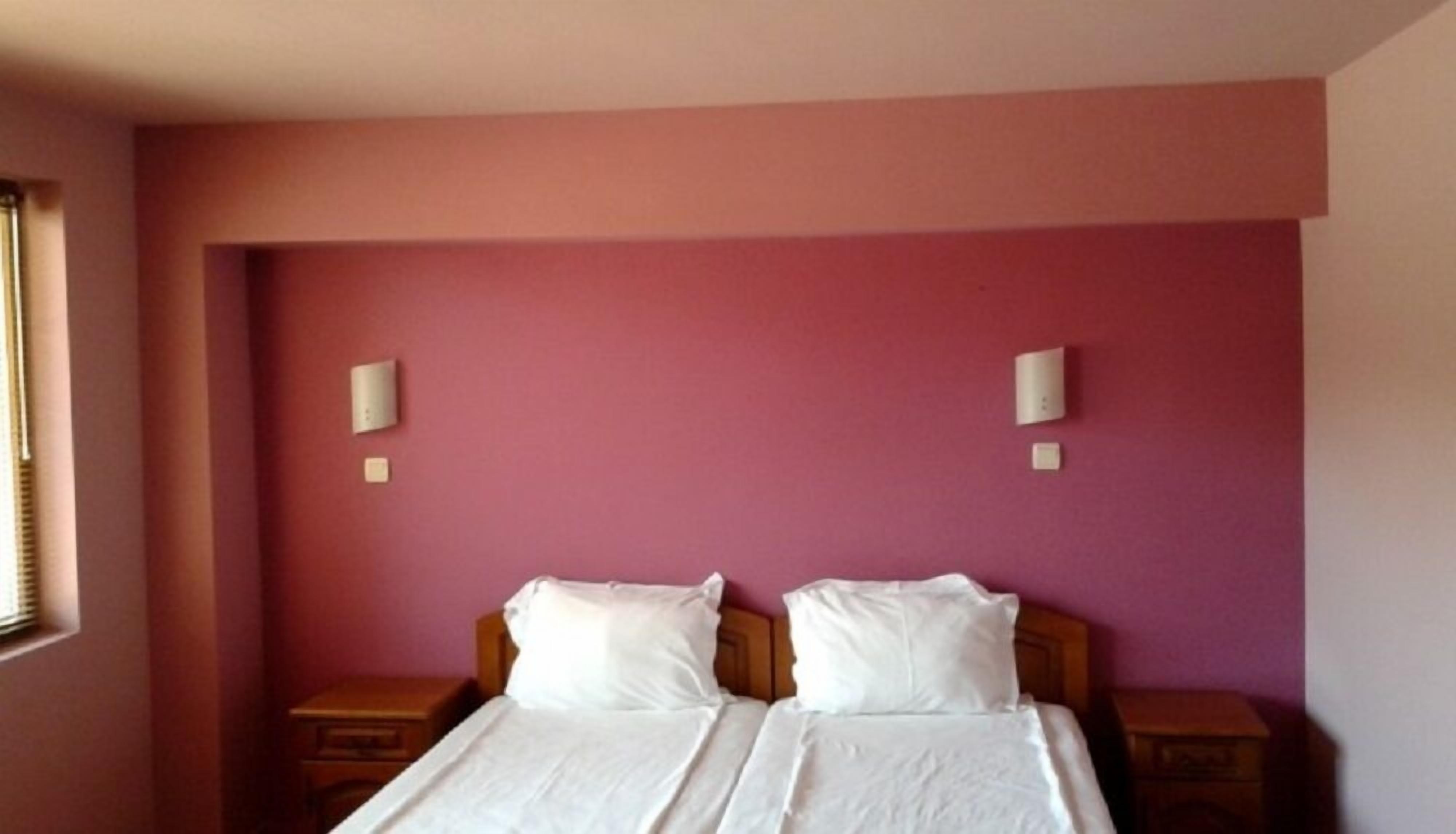 A room with two beds, a window, and two bedside tables.