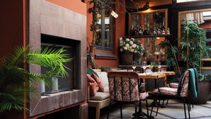 A cozy outdoor seating area with a fireplace, comfortable chairs, and a variety of plants. - Hotel Sanders (Copenhagen)