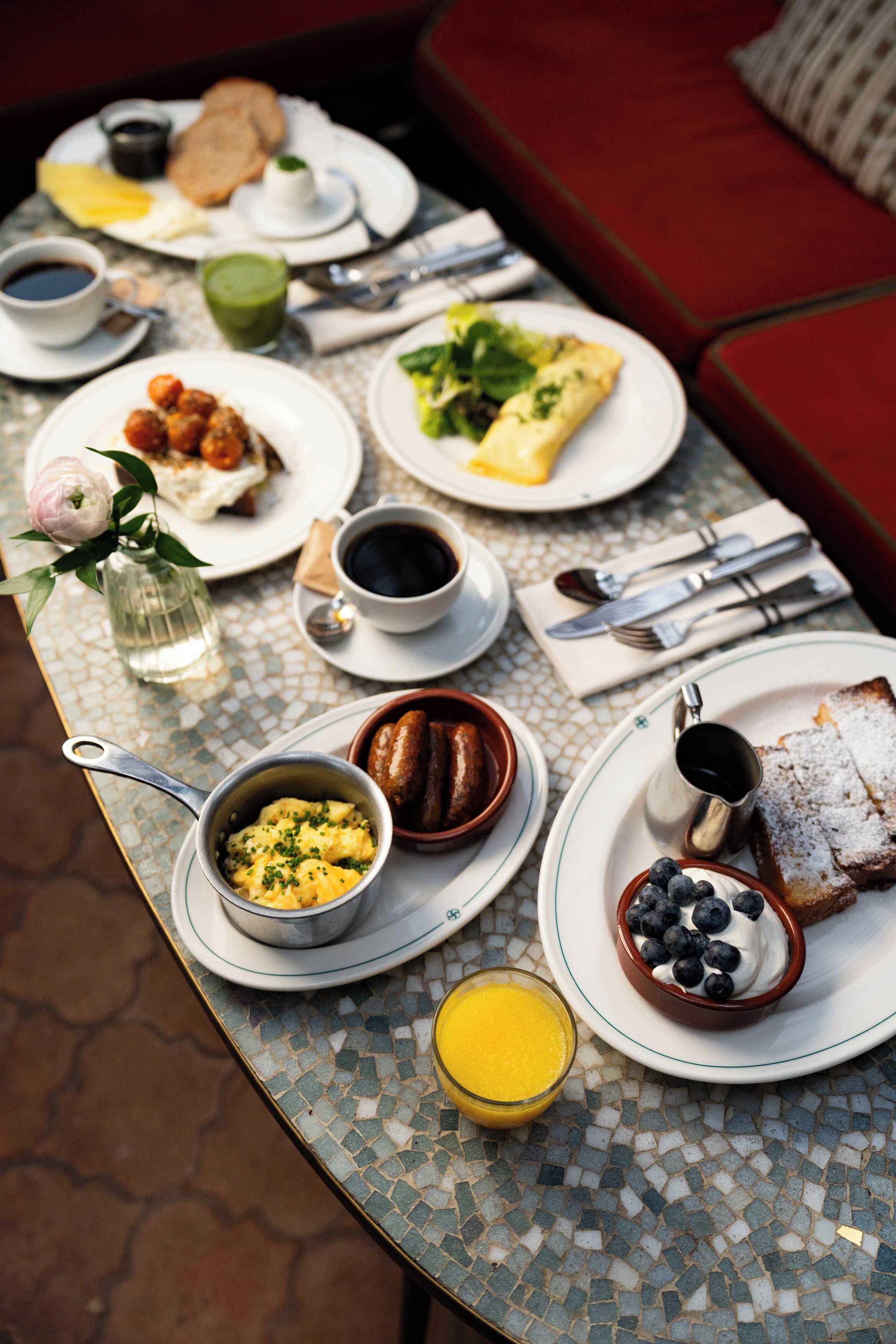 A breakfast table with various dishes, including eggs, toast, and a glass of orange juice.