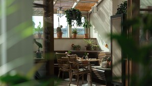 A cozy indoor seating area with wicker chairs and a bench, surrounded by potted plants and a view of the outdoors. - Hotel Sanders (Copenhagen)