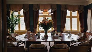 Comedor con una mesa redonda, sillas, un jarrón de flores y cortinas.