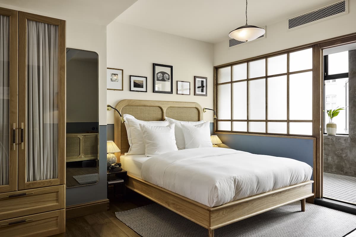 Un dormitorio con cama, armario de madera y un ventanal grande.