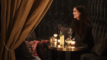 A cozy seating area with a round table, candles, and a bottle of wine.