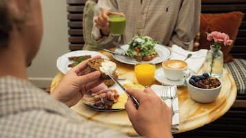 A breakfast setting with a table set for two, including plates with food, a coffee cup, and a glass of orange juice.