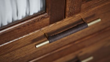 Een houten deurklink met een messing stang en een geribbelde greep.