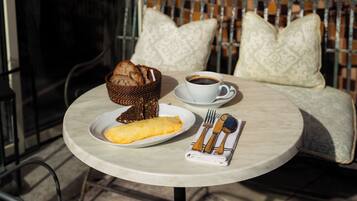 A round table with a plate of food, a cup of coffee, and cutlery.