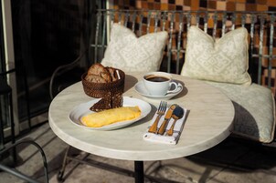 A round table with a plate of food, a cup of coffee, and cutlery.