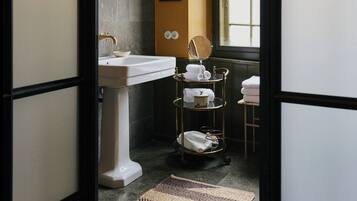 A bathroom with a white pedestal sink, a mirror, and a towel rack.