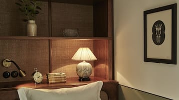 Una estantería de madera bien ordenada con una lámpara, libros, un reloj y un cuadro enmarcado.