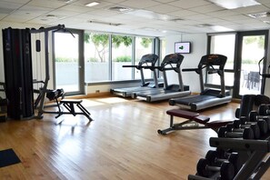 Une salle de sport équipée de tapis de course, d’un banc de musculation et de poids libres.