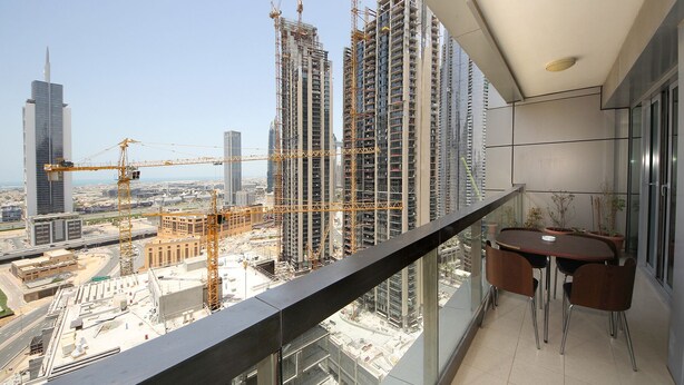A balcony with a view of a cityscape, including high-rise buildings and construction cranes. - New Arabian Holiday Homes - 8 Boulevard (Dubai)
