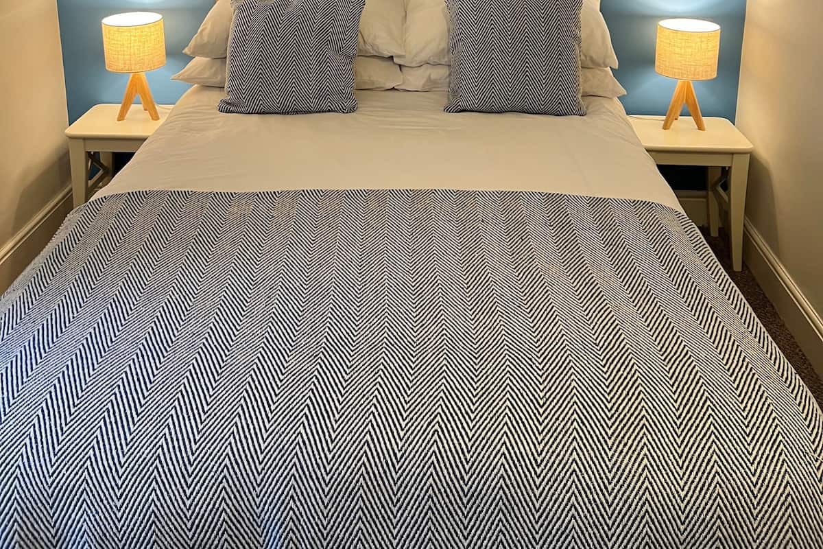 Un dormitorio con una cama, dos mesitas de noche y dos lámparas.