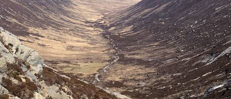 A mountainous landscape with a valley and a distant body of water.