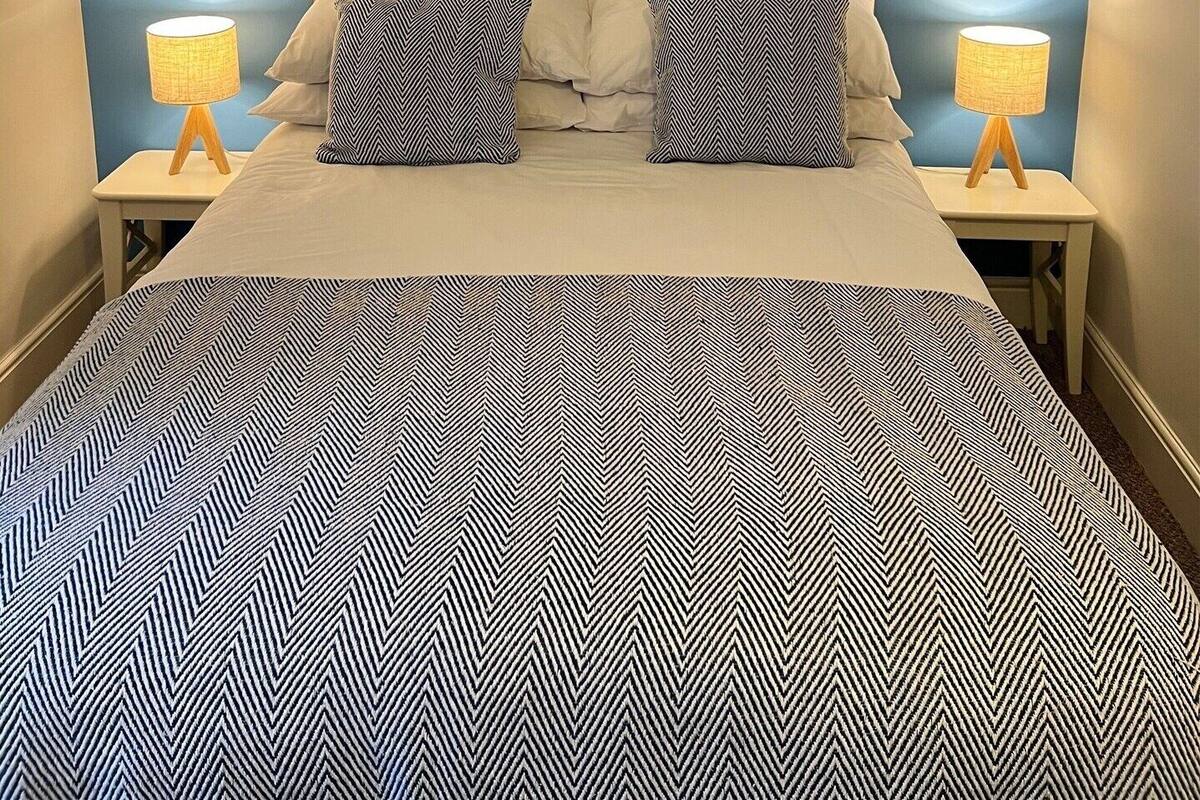 Un dormitorio con cama, dos lámparas de noche y una pared de acento azul.