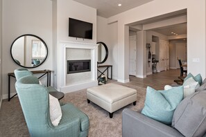 A living room with a fireplace, two sofas, a television, and a dining area in the background. - Stylish 3BR w/ Fireplace - Near Pool & 18th Hole (St. George)