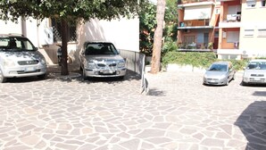 A paved driveway with parked cars and a tree. - Ianus Guest House (Rome)
