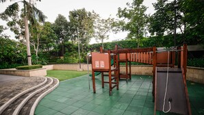 A playground with a slide and swings, surrounded by greenery and a brick pathway. - Saigon City View Apartment & Pool (Ho Chi Minh City)