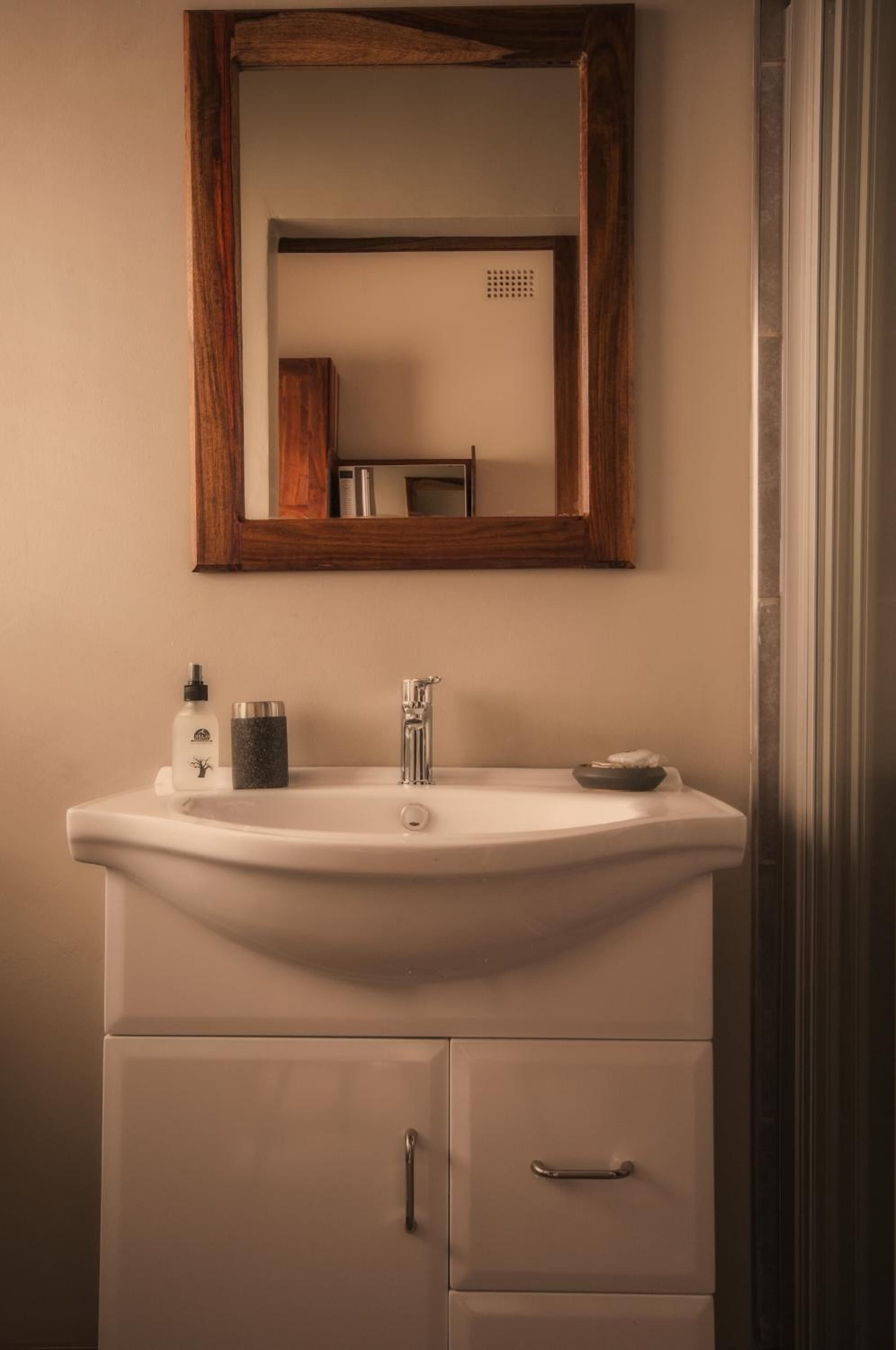 A bathroom with a white sink, a wooden-framed mirror, and a cabinet with two drawers.