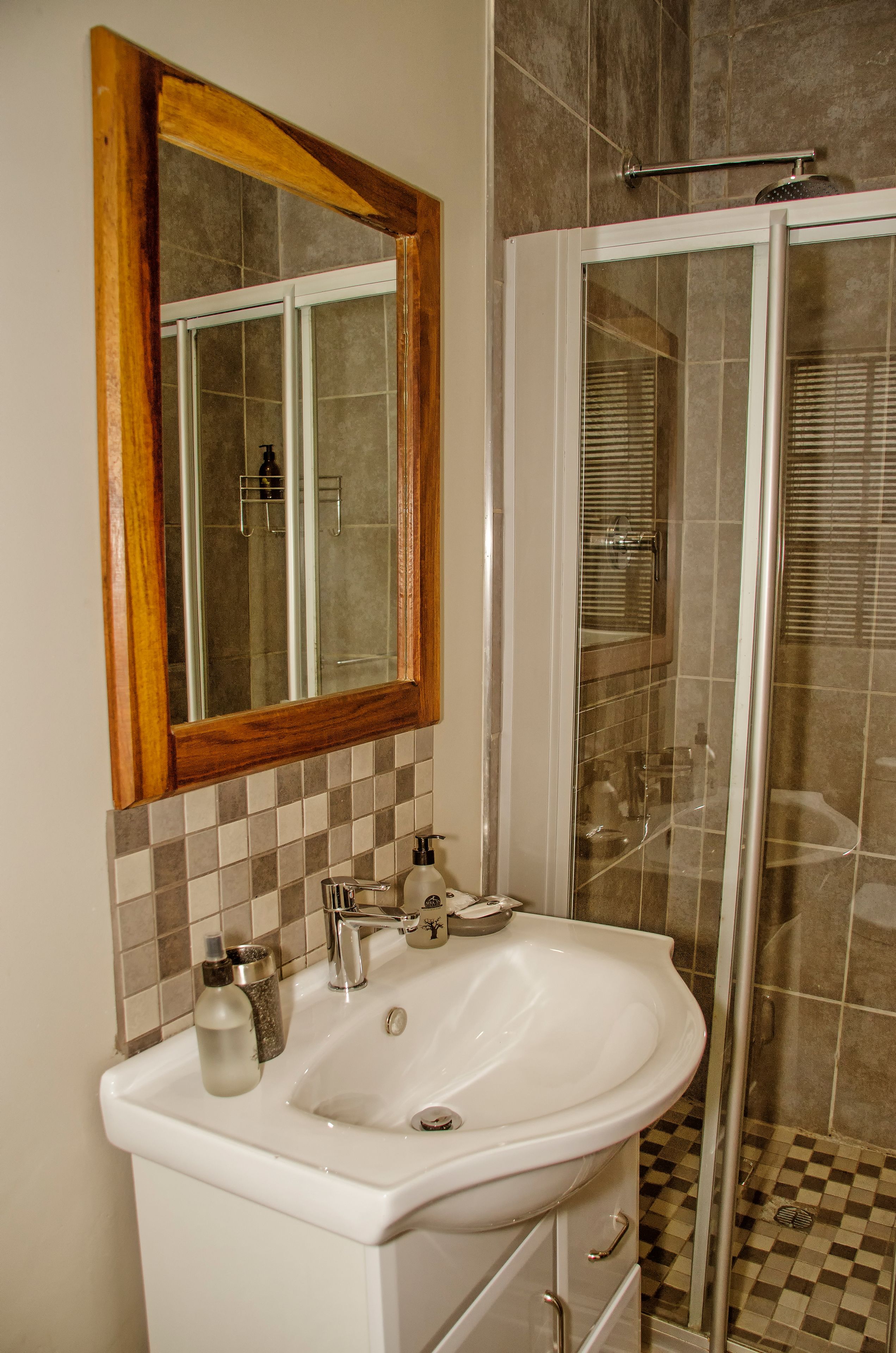 A bathroom with a white sink, a mirror with a wooden frame, and a shower area.