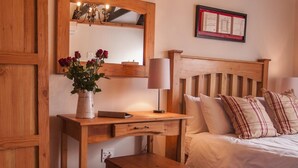 Un dormitorio de madera con una cama, un escritorio y un espejo.