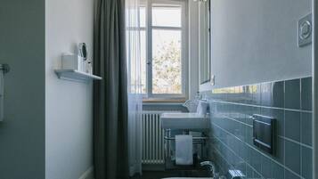 A narrow bathroom with a window, a sink, and a toilet.