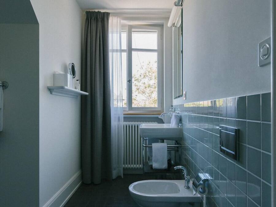 A narrow bathroom with a window, a sink, and a toilet.