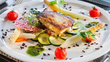 A plate of food with various vegetables and a piece of grilled fish.