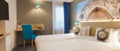 Habitación de hotel con una cama grande, un escritorio, una silla, un televisor y una lámpara en la pared.