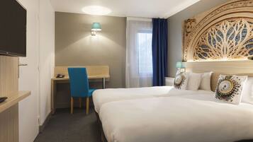 A hotel room with two beds, a desk, a chair, a television, and a decorative headboard.