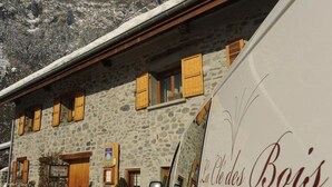 Un bâtiment en pierre avec des volets en bois et un panneau indiquant un parking.