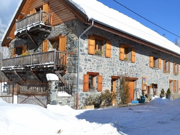Un bâtiment en pierre doté de balcons en bois et d’un toit recouvert de neige.
