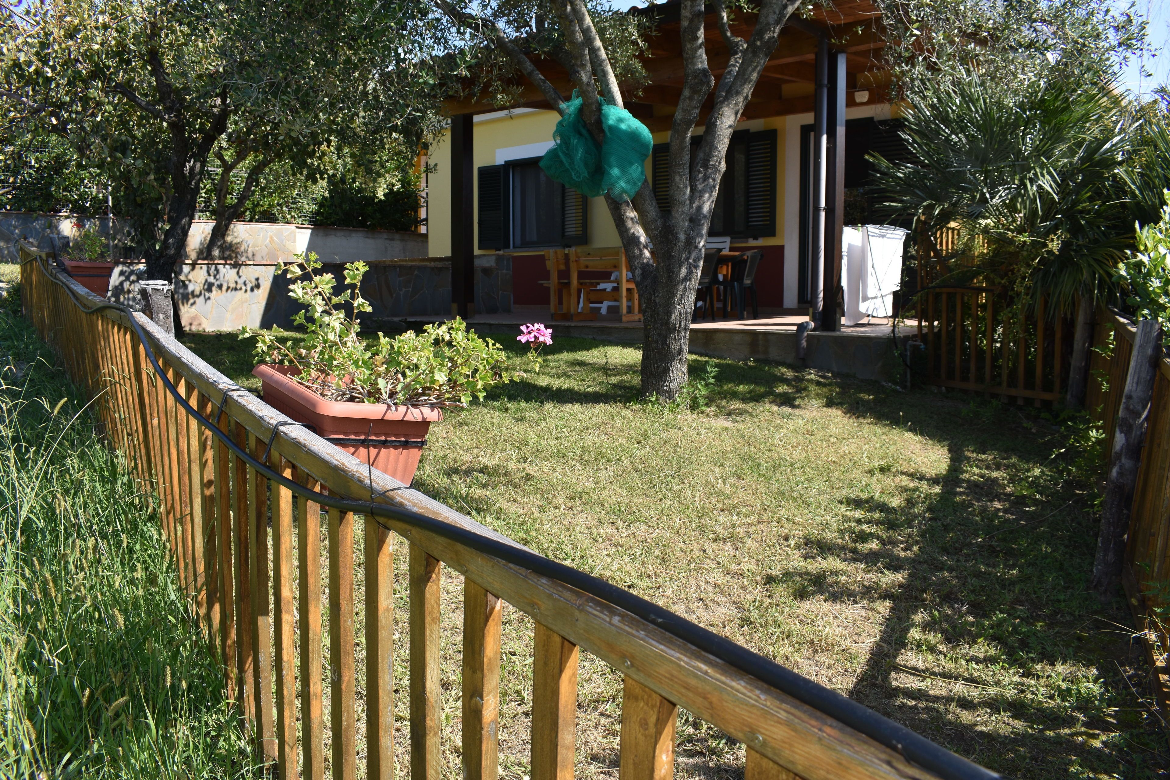 Une clôture en bois, un arbre et un bâtiment doté d’un porche.