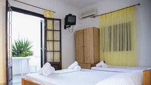Une chambre avec deux lits, une armoire en bois, un téléviseur et un appareil de climatisation.