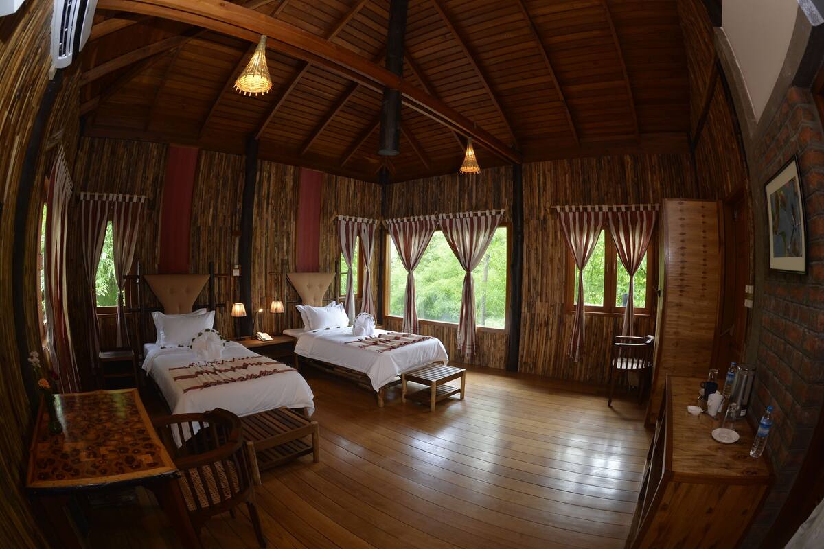 A wooden cabin with two beds, a dining table, and a bench.