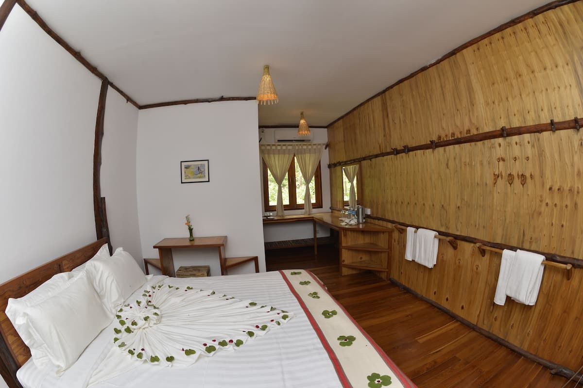 A room with a wooden bed, a small desk, and a wooden wardrobe.