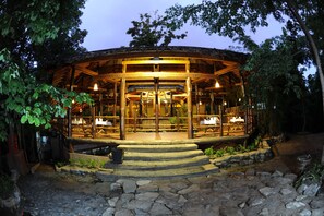 A wooden gazebo-style structure with a thatched roof, surrounded by greenery, and illuminated by hanging lights. - Bago Yoma Eco Resort (Paukkaung Township)