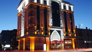 Un hotel con una amplia entrada en arco, varios balcones e iluminación de señalización.