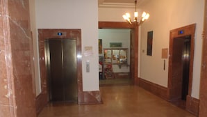 A hallway with two elevators, marble flooring, and a chandelier. - Almog Studio (Haifa)